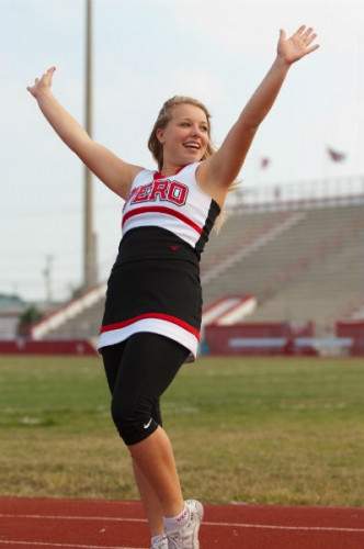Teenage cheerleader posing with arms in a V.
